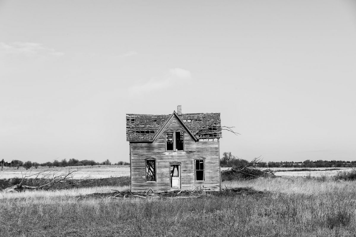 Black and white photograph of an abandoned farm house on the Kansas prairie