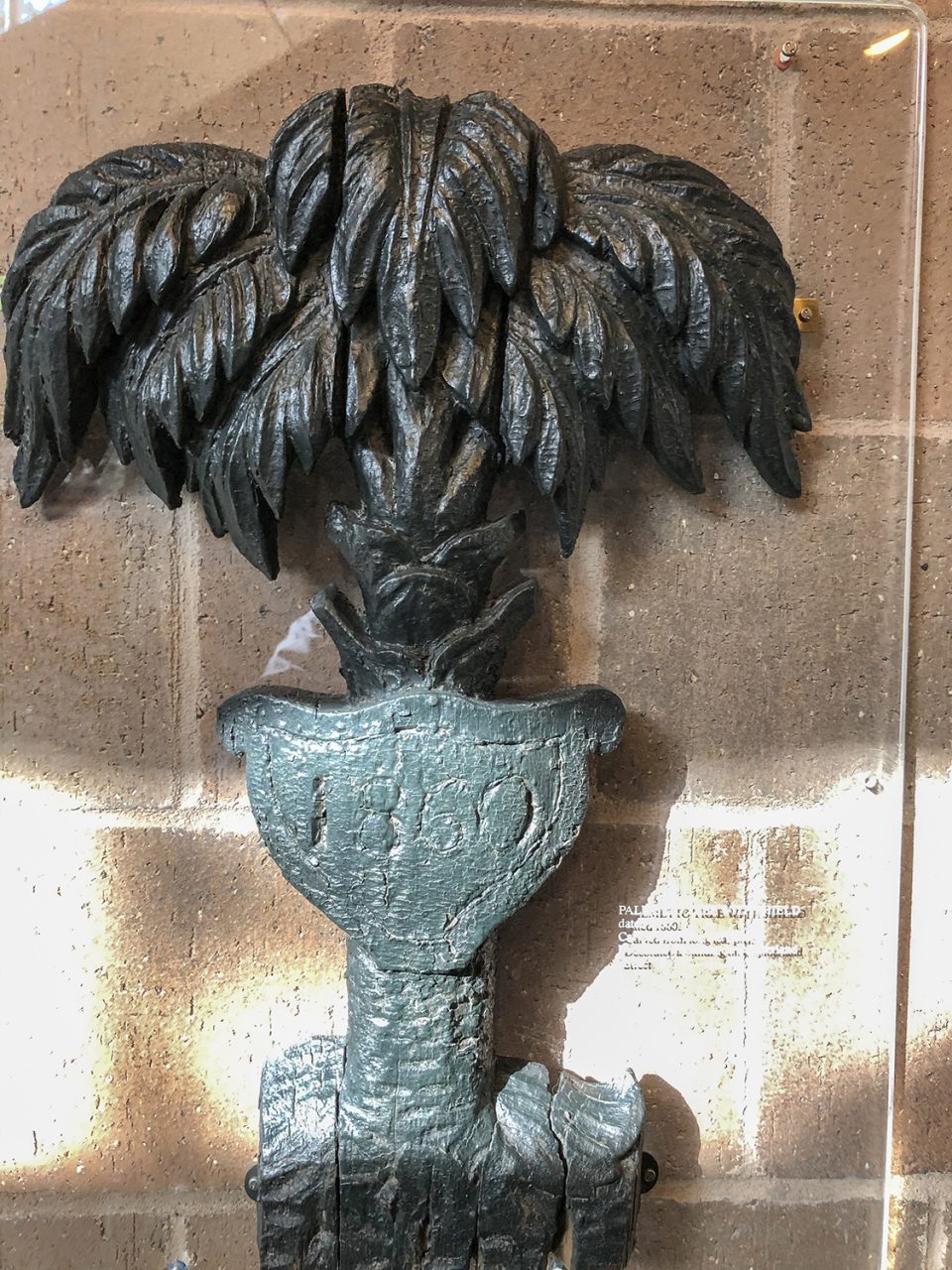 Photo of a cast iron palm tree with a shield dated 1860, as seen in the Charleston Museum.