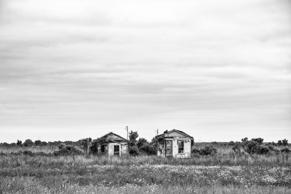 Abandoned shotgun shacks located on the highway between Clarksdale and Belzoni, Mississippi. Black and white photograph by Keith Dotson. Buy a fine art print.
