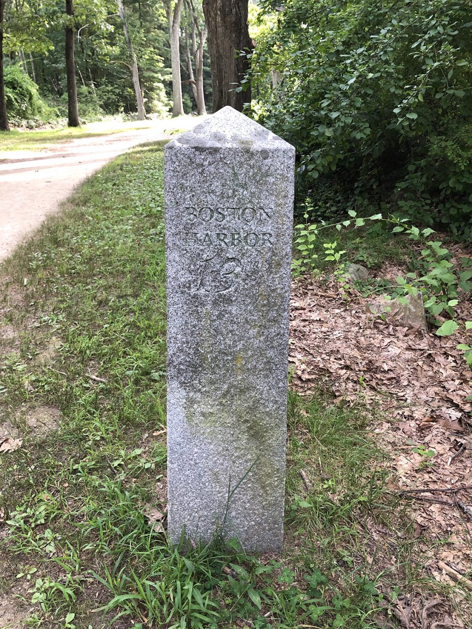 A granite milestone marker along the old Bay Road, now called the battle road, marks the distance to Boston Harbor (13 miles)