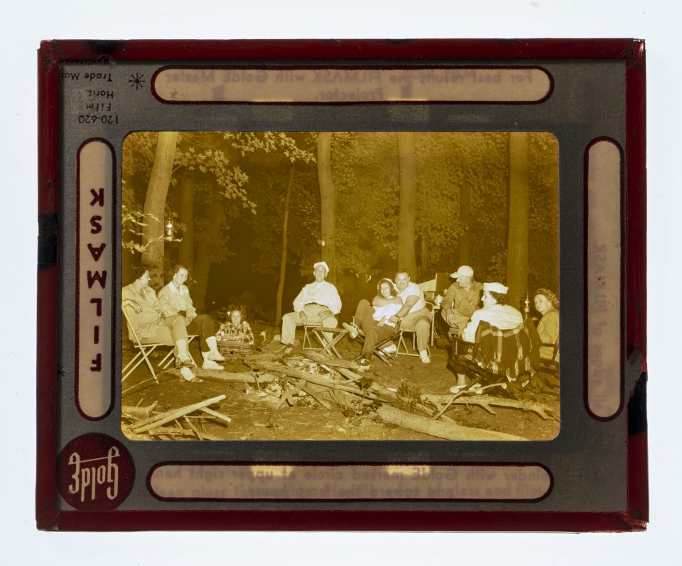 A sepia-toned monochrome photograph of the family sitting in chairs in the forest.