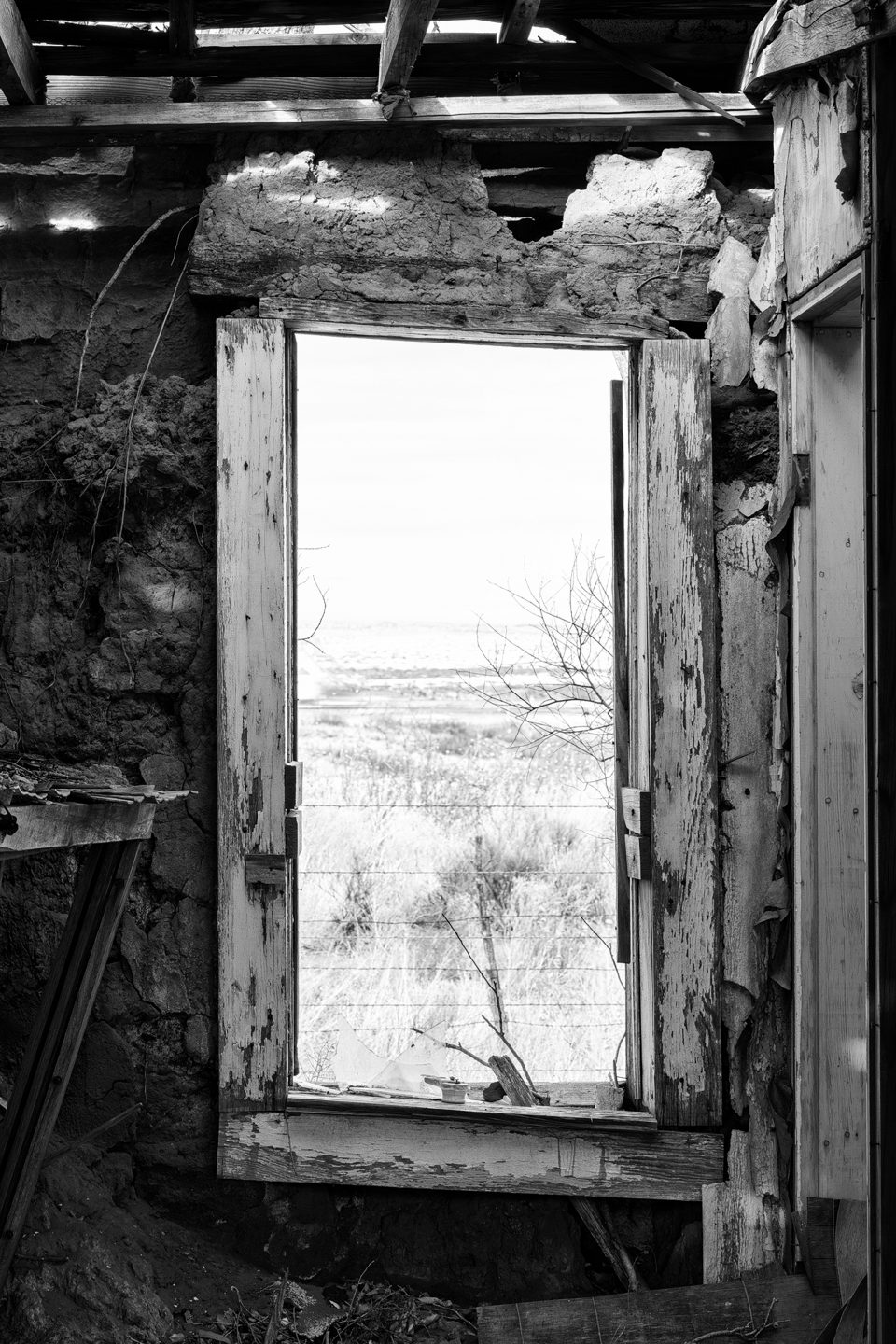 The New Mexico landscape seen through a broken window of a room in the collapsing State Line Motel built 1930 in Glenrio.