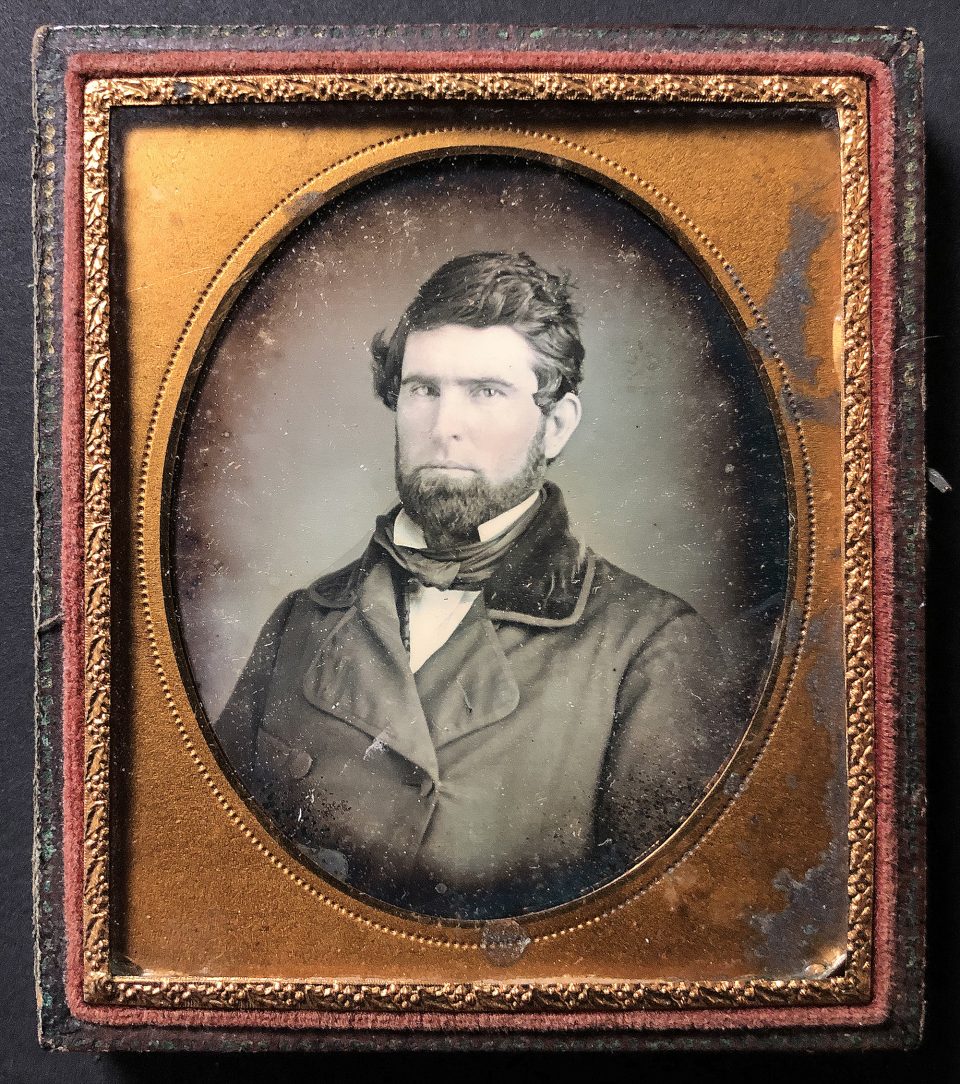 Daguerreotype portrait of a man with a beard and wearing his overcoat, circa the 1840s. Photographer, location, and subject are all unknown.