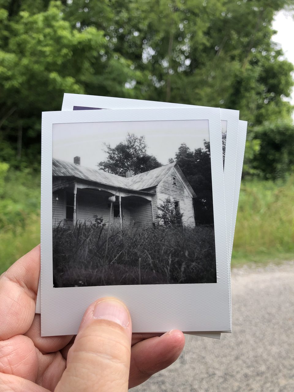 Here we can see a black and white Polaroid photograph of the same old farmhouse shown before.