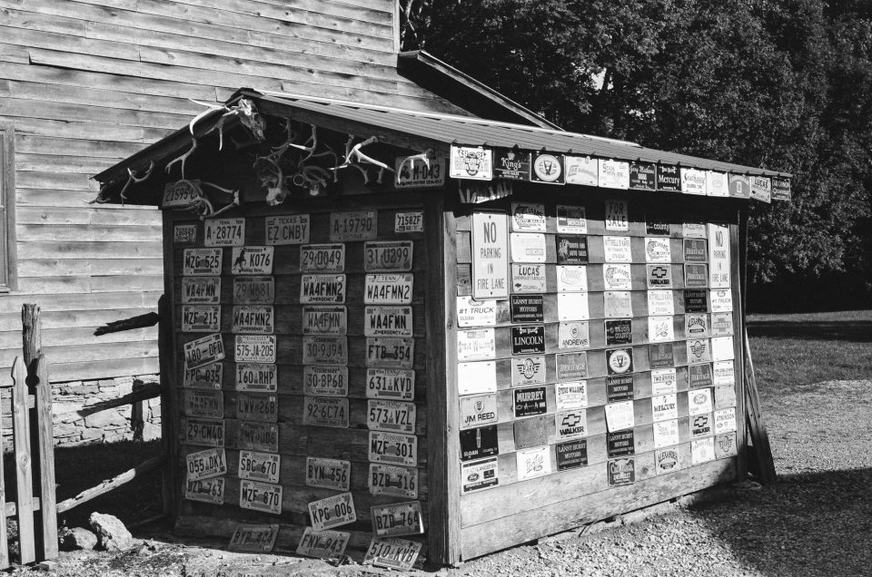Photograph of a wooden shed covered in old car license plates taken by Keith Dotson. Shot on Kodak Tri-X black and white film using a 40-year-old Pentax K1000 camera and 50mm lens.