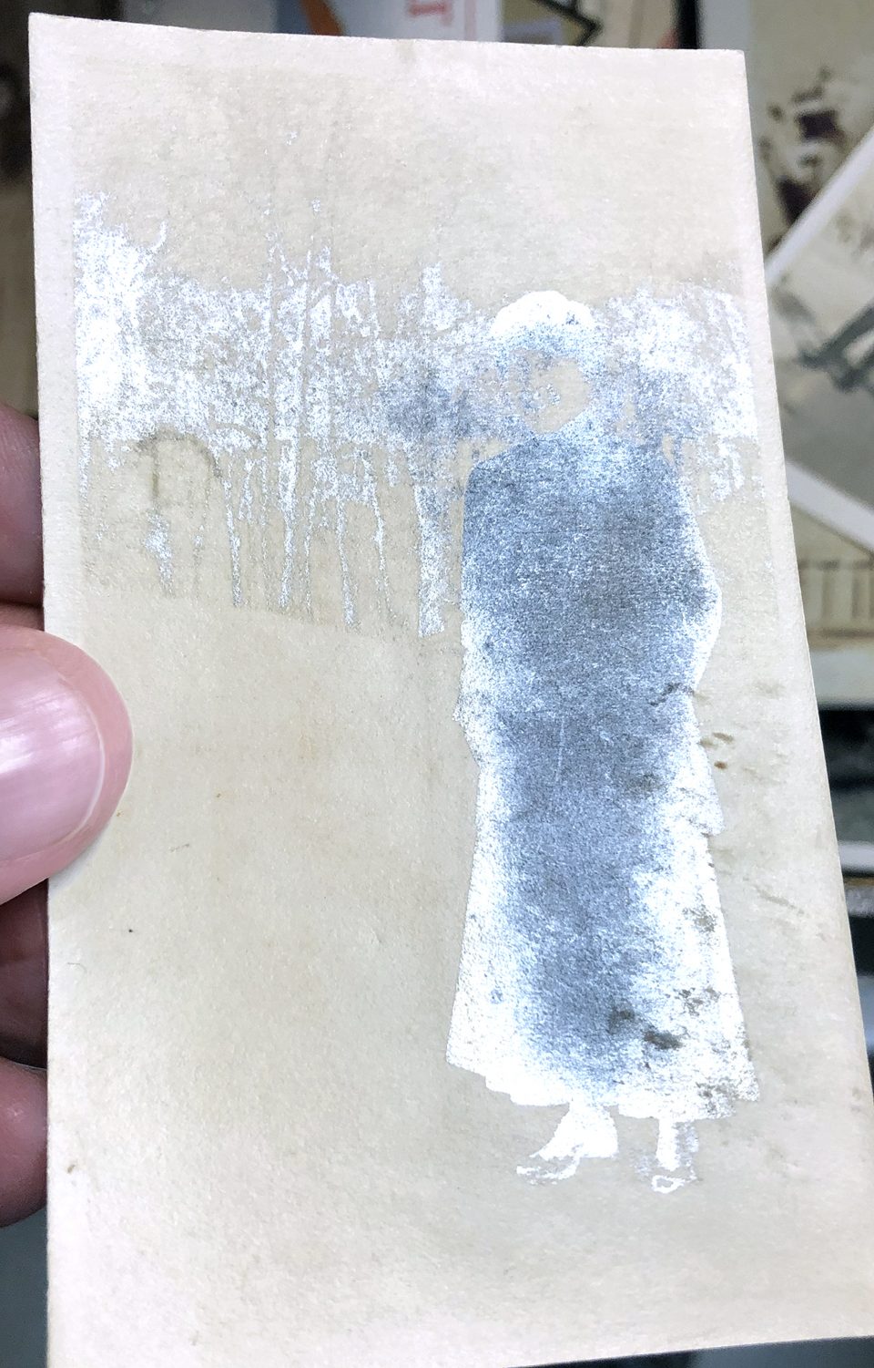When turned to the light, this turn-of-the-century snapshot of a lady standing in the snow shows the distinct symptoms of silver mirroring decay.