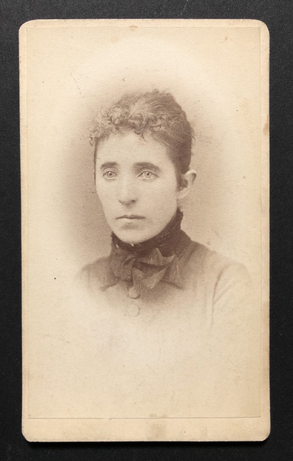 Head and shoulders portrait of a somber young woman in carte de visite size, made by the studio of W.H. Jacoby of Minneapolis.