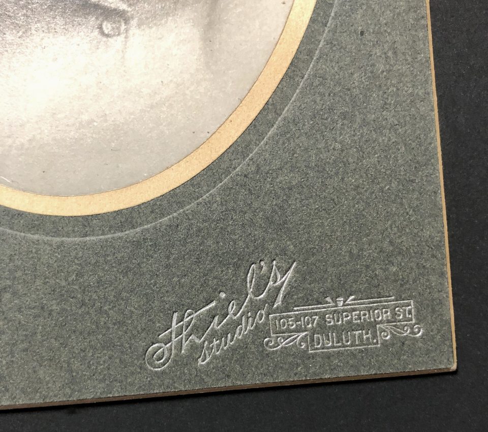 A detail look at the Thiel’s Studio logo foil stamped in silver onto the bottom right corner of this cabinet card.