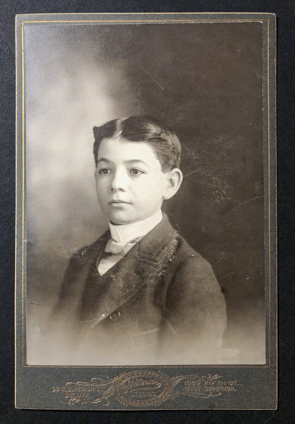 Head and shoulders portrait of a young boy with an overcoat and spiffy bowtie, shot by the Christensen Studios in either Duluth or West Superior, Wisconsin.