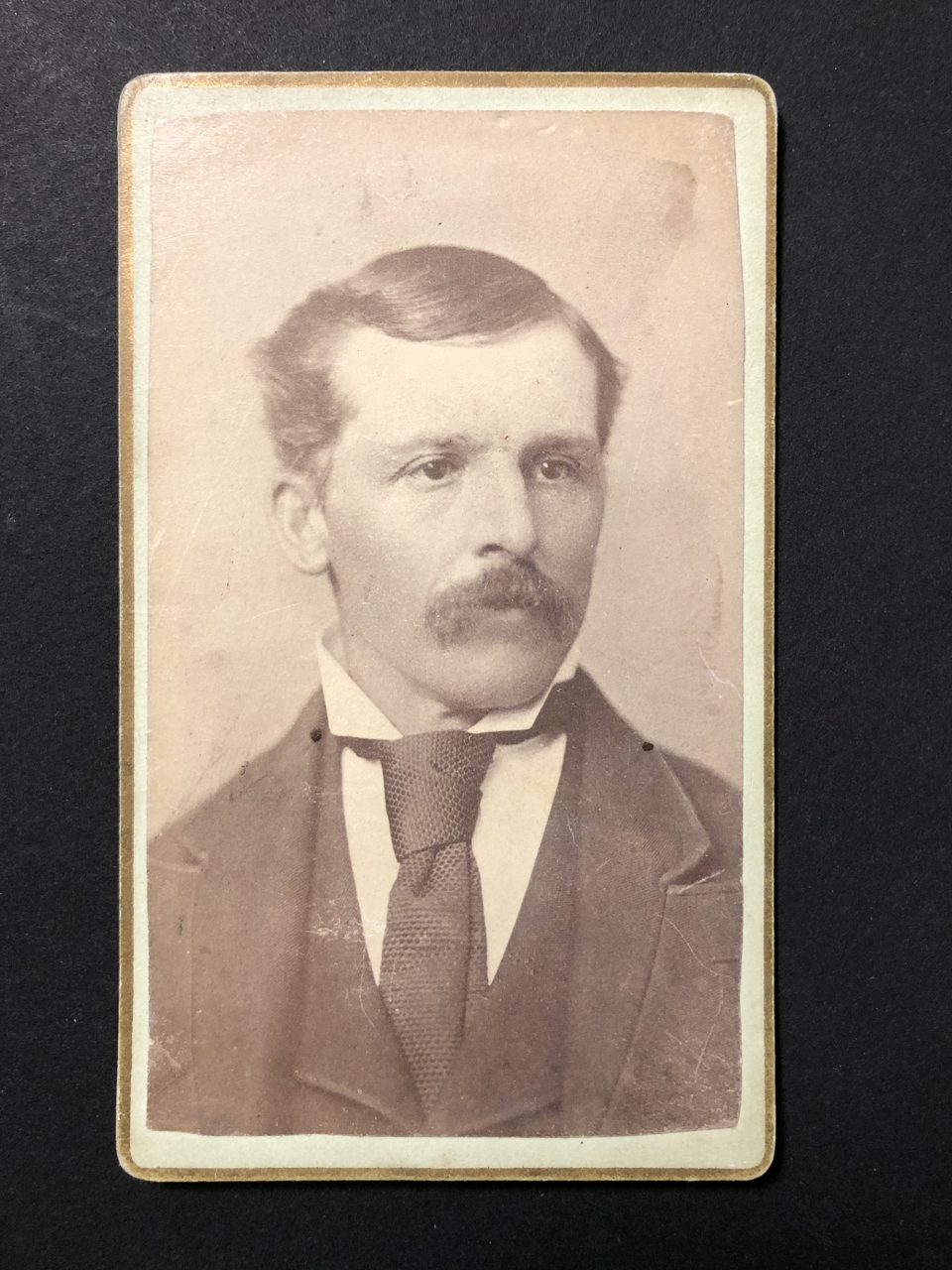 Head and shoulders portrait of a man with a mustache and necktie with a very wide knot, made by photographer A.A. Scott of Hastings, Minnesota.