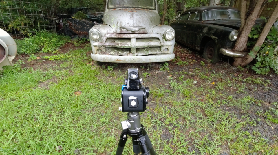 A behind-the-scenes on location photo shows the Hasselblad 500C/M in position to shoot one of the old trucks
