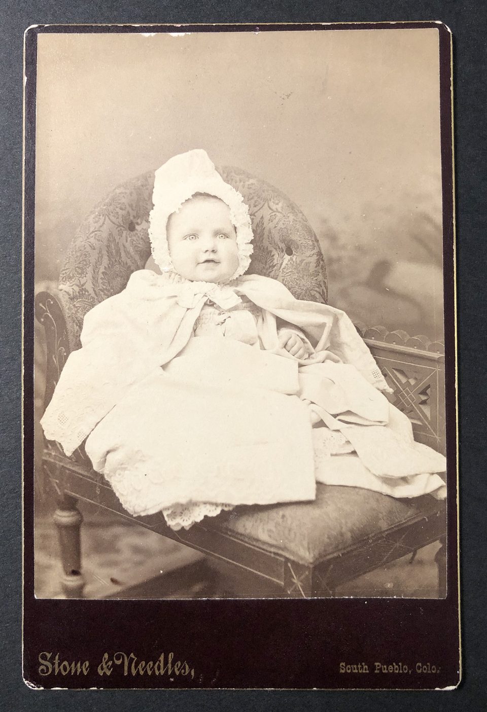Cabinet card portrait of a smiling infant, photographed by the studio of Stone & Needles in South Pueblo,
