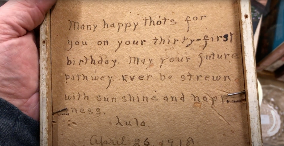 Le dos de la photographie encadrée de la femme écrivant des lettres montre un message d'anniversaire manuscrit