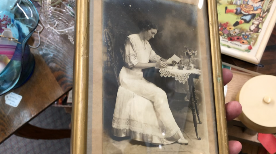 Belle photographie d'une femme en longue robe blanche travaillant sur sa correspondance, vers 1918