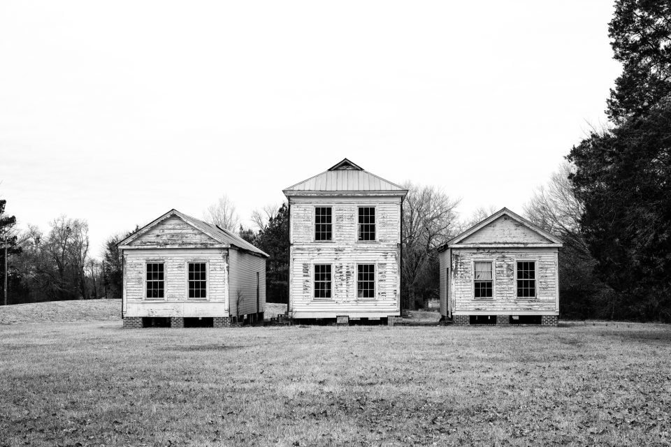 Trois structures historiques en planches à clin blanches se tenant côte à côte à Newbern, en Alabama.  Photographie en noir et blanc de Keith Dotson.