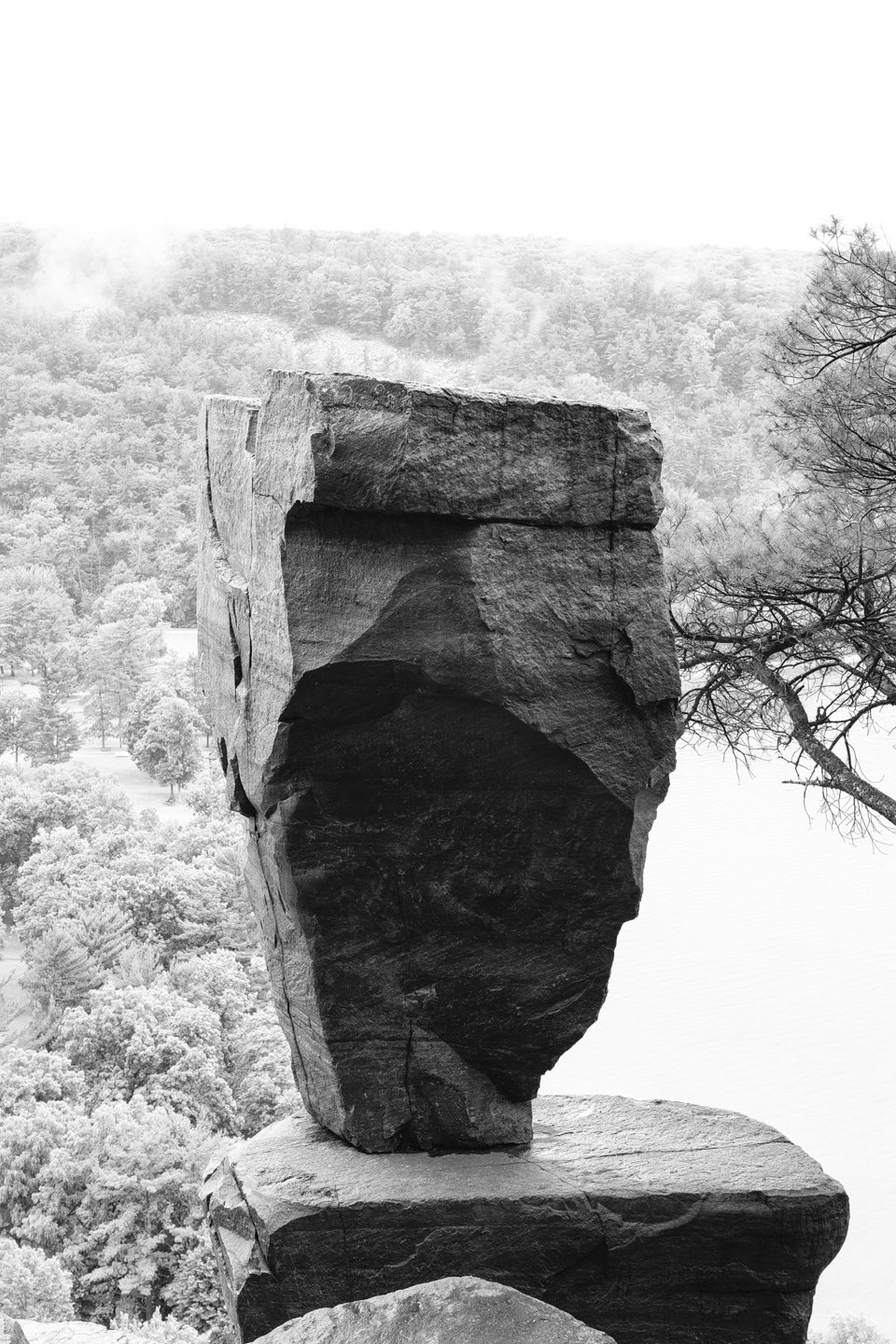 A landscape photograph in black and white of the balanced rock seen overlooking Devil's Lake in Wisconsin.