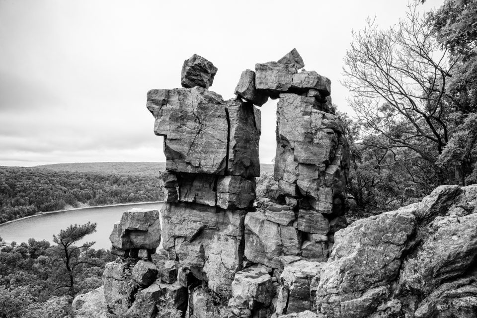 Black and white photograph of a magnificent rock formation called the Devil's Doorway, seen at Devil's Lake in Wisconsin