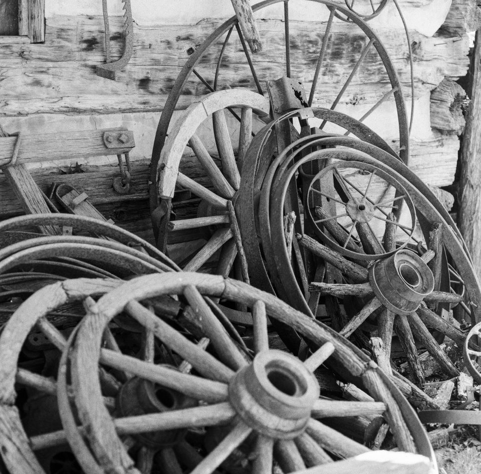 Black and white photograph of a pile of old wagon wheels at Museum of Appalachia in Tennessee, shot on Fomapan 100 film with Hasselblad 500 C/M camera by Keith Dotson.