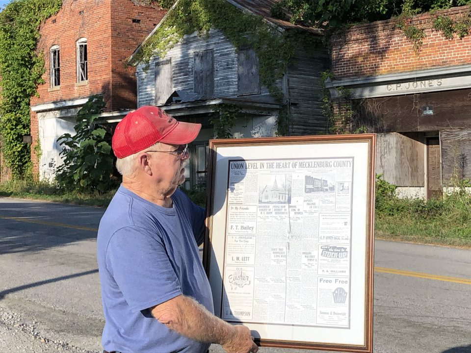 James O. (Jimmy) Thompson holding a 1938 newspaper page with ads and stories about Union Level, Virginia.