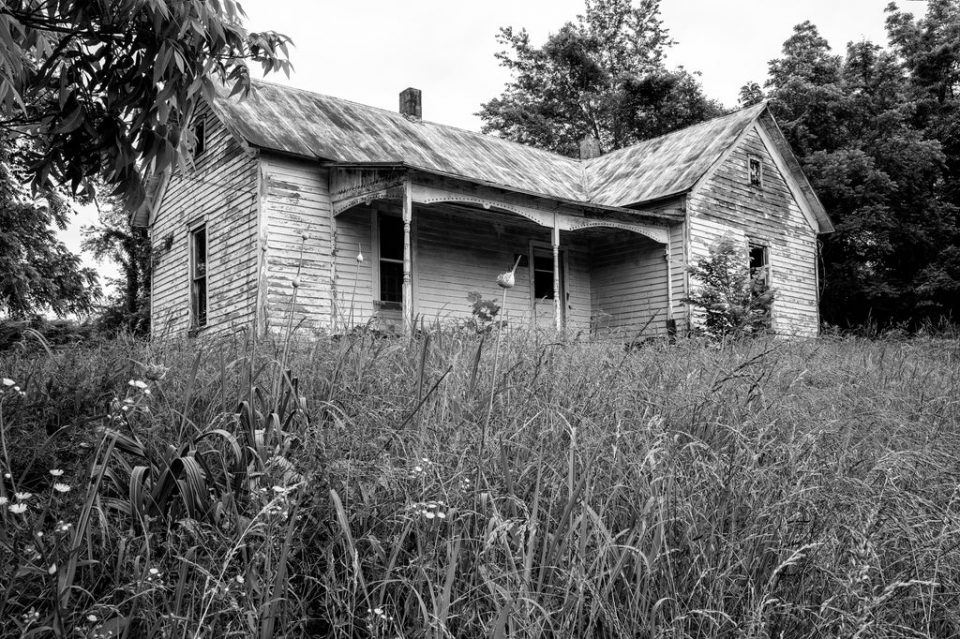 Black and white photograph of an abandoned farmhouse which has since been demolished
