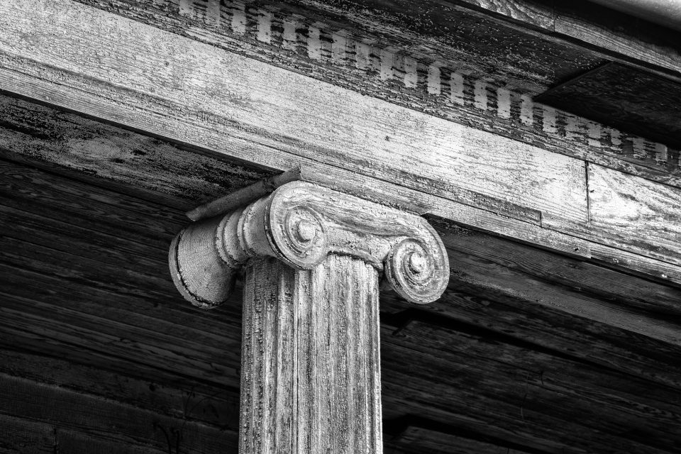 This detail photograph shows the cracks in the many coats of white paint on the weathered wood. It also shows the the architectural features known as dentils have long since been removed. Black and white photograph by Keith Dotson. Buy a fine art print here.