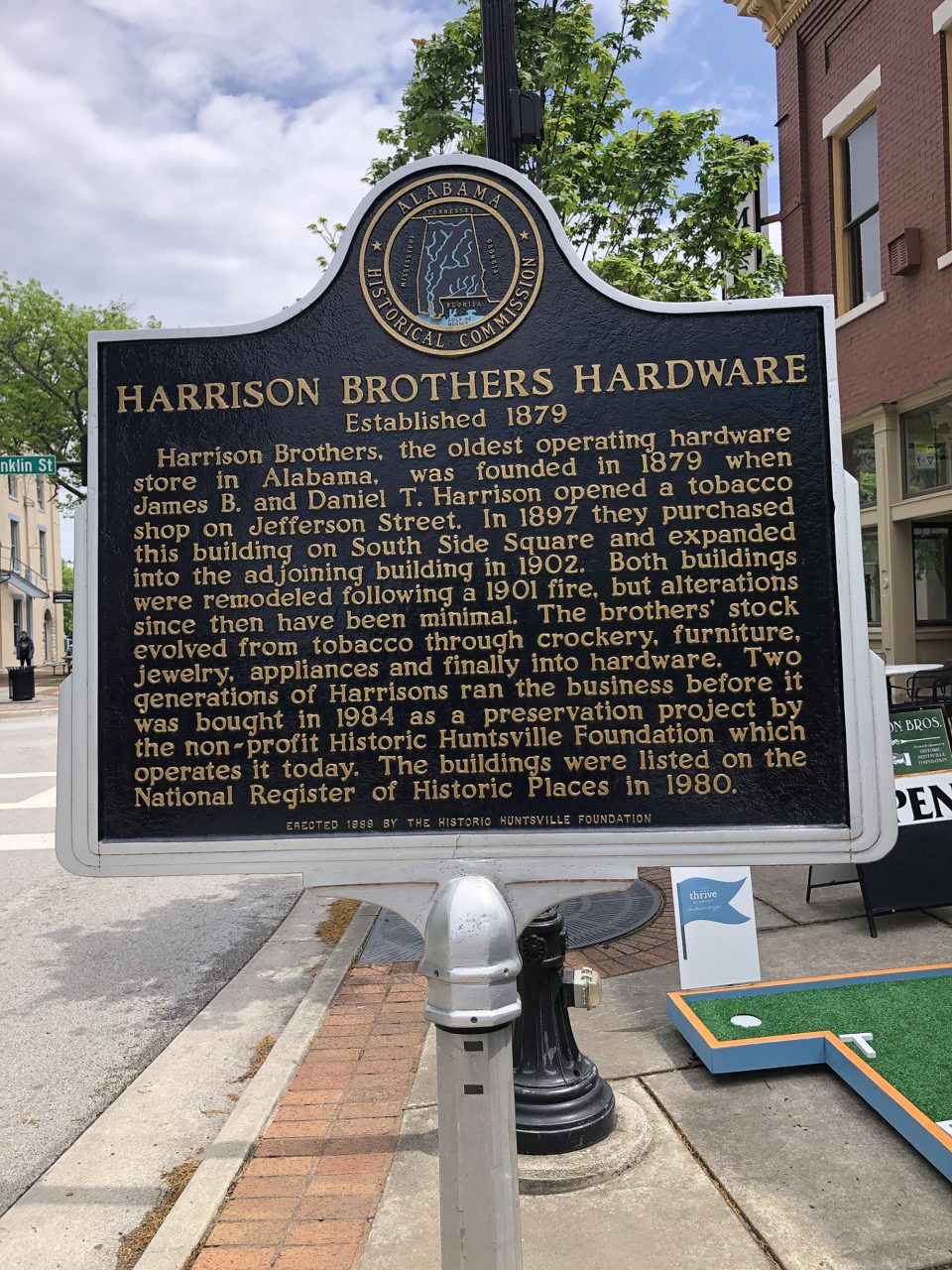 Historical marker on the sidewalk in front of Harrison Brothers Hardware, established 1879, and at this location since 1897.