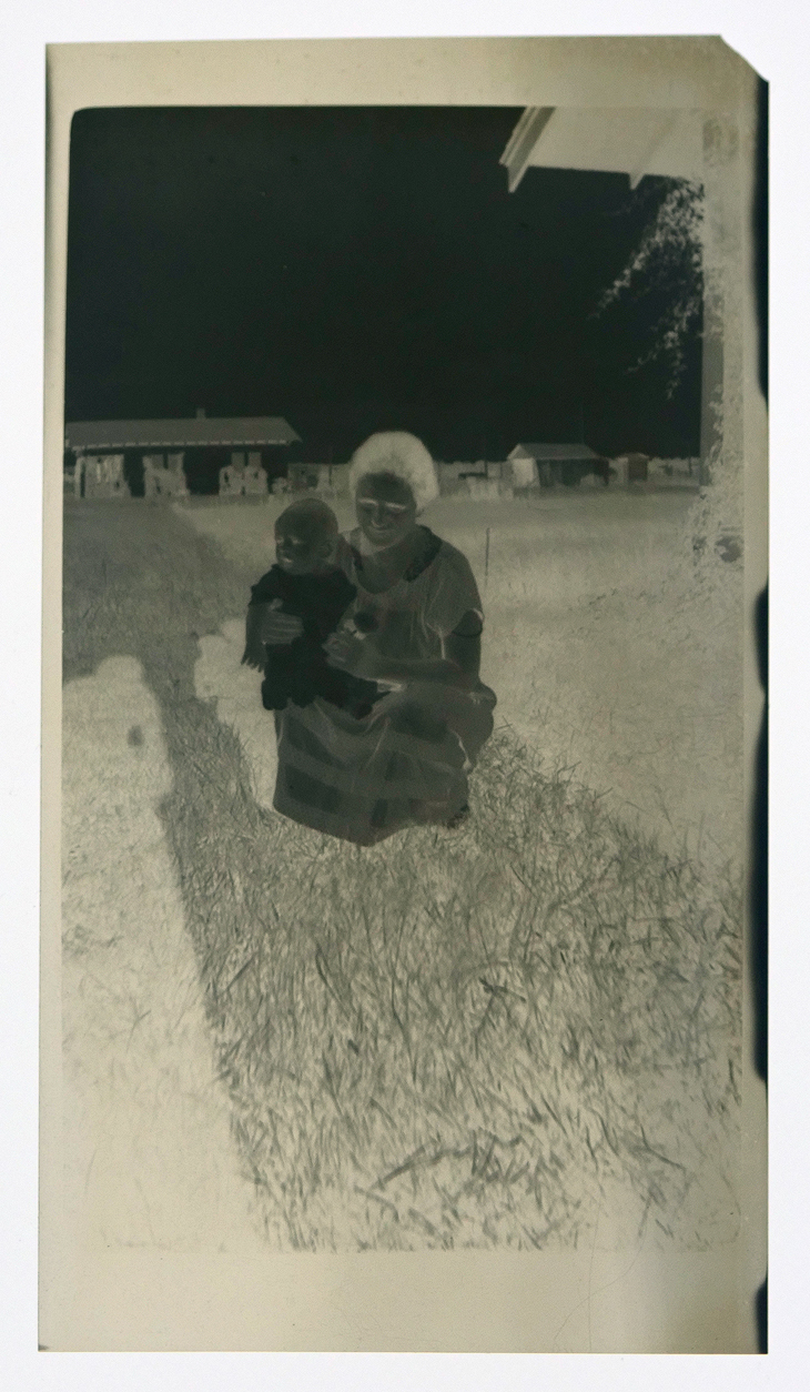 Film negative with a mother and child kneeling in the grass.