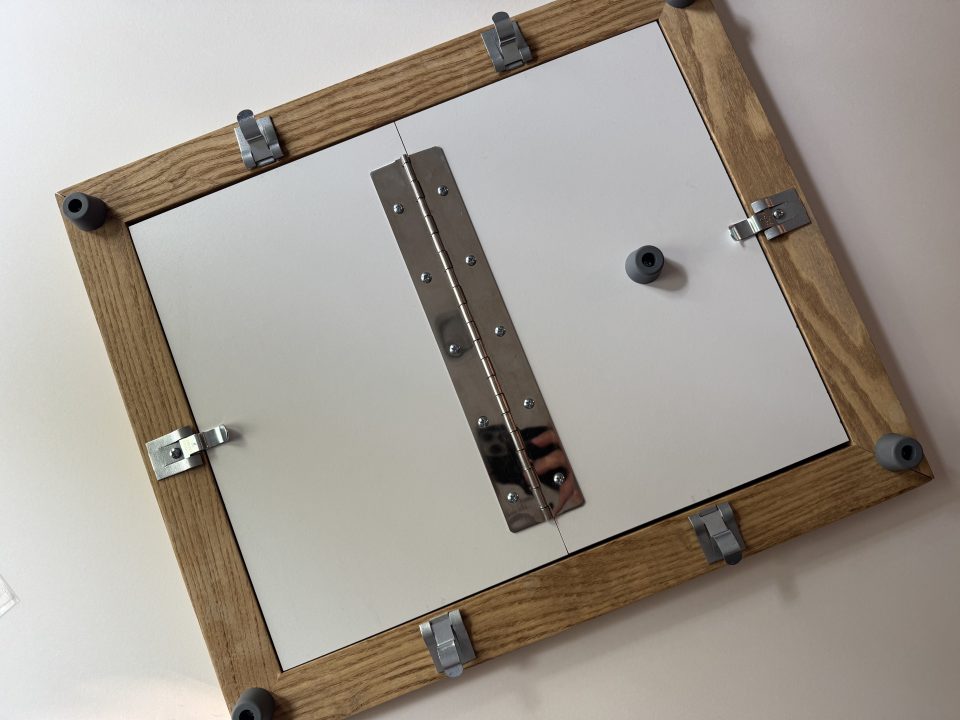  This image shows the the folding back of a contact printing frame, which allows you to check the exposure of the print without shifting the negative out of place.