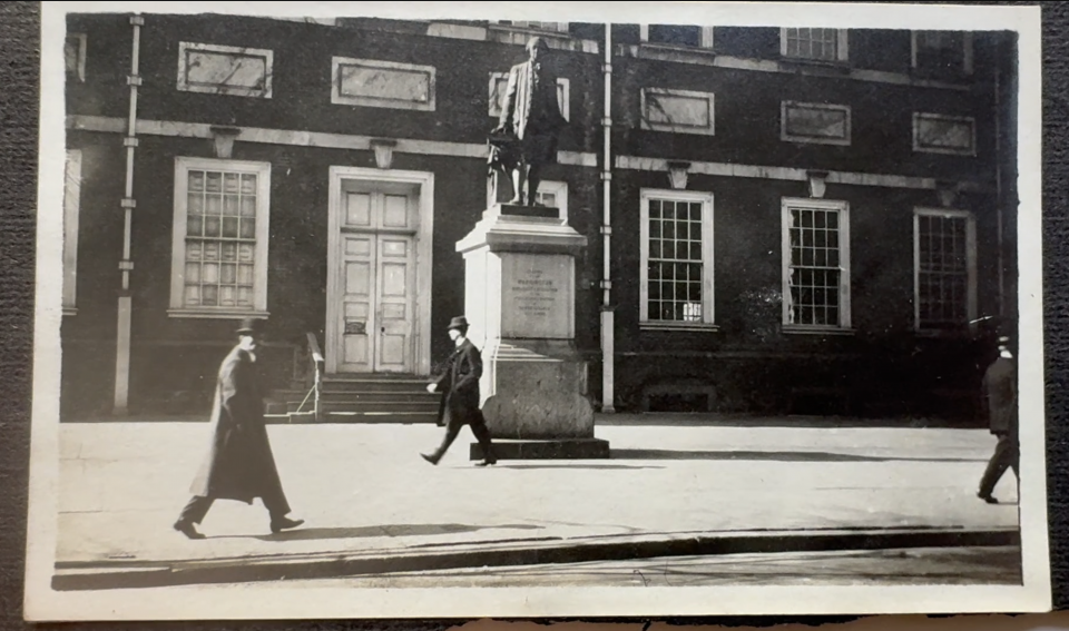A black and white snapshot of Independence Hall in Philadelphia, with passers-by shot in 1916.