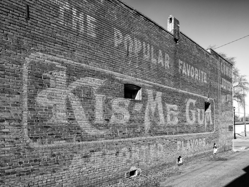 Keith Dotson's black and white photograph of a vintage faded wall ad for Kis-Me-Gum fruit flavored chewing gum