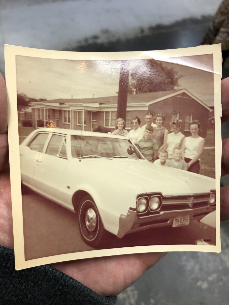 late '60s or early '70s snapshot where we see a large family positioned behind a white car. I can't quite make out the state name on the license plates nor the model name that's set above the front grill. And since so many of the ladies have curlers in their hair, I assume it was an impromptu photograph.