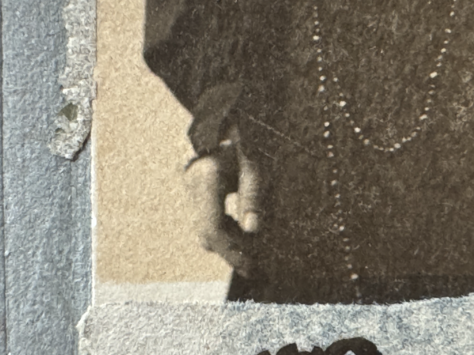 This extreme close-up of the photograph's surface shows how much the exposed part of the photograph has yellowed, compared to the part that would have been concealed away from light under the mat.