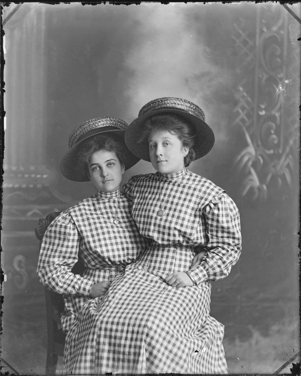 According to AI, gingham became an immensely popular fabric choice in the late 1890s for casual, everyday attire. The style—featuring high, stiffened collars and puffed sleeves—points toward a late 1890s construction that maintained its popularity in rural and Midwestern locales like Kansas into the very early 1900s. Their hairstyles and big straw boater hats -- which AI called quintessential accessories for young women during this five-year window -- were other signature points that helped AI determine the date range. 
