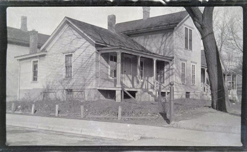 Photograph of a large house that appears to be in a town or neighborhood.