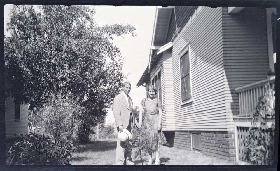 A young couple standing in the side yard of the house in town.