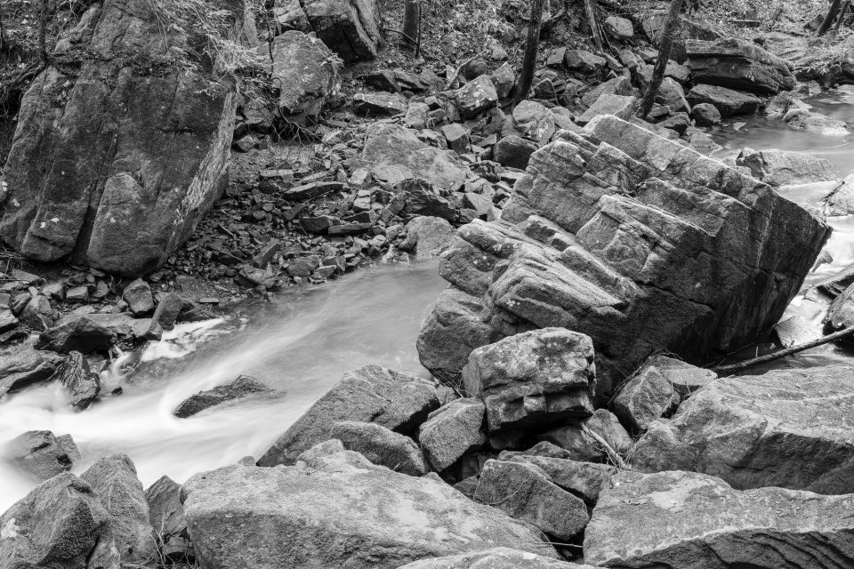 Black and white landscape photograph of massive rocks along a rushing stream in Tennessee's Savage Gulf State Park