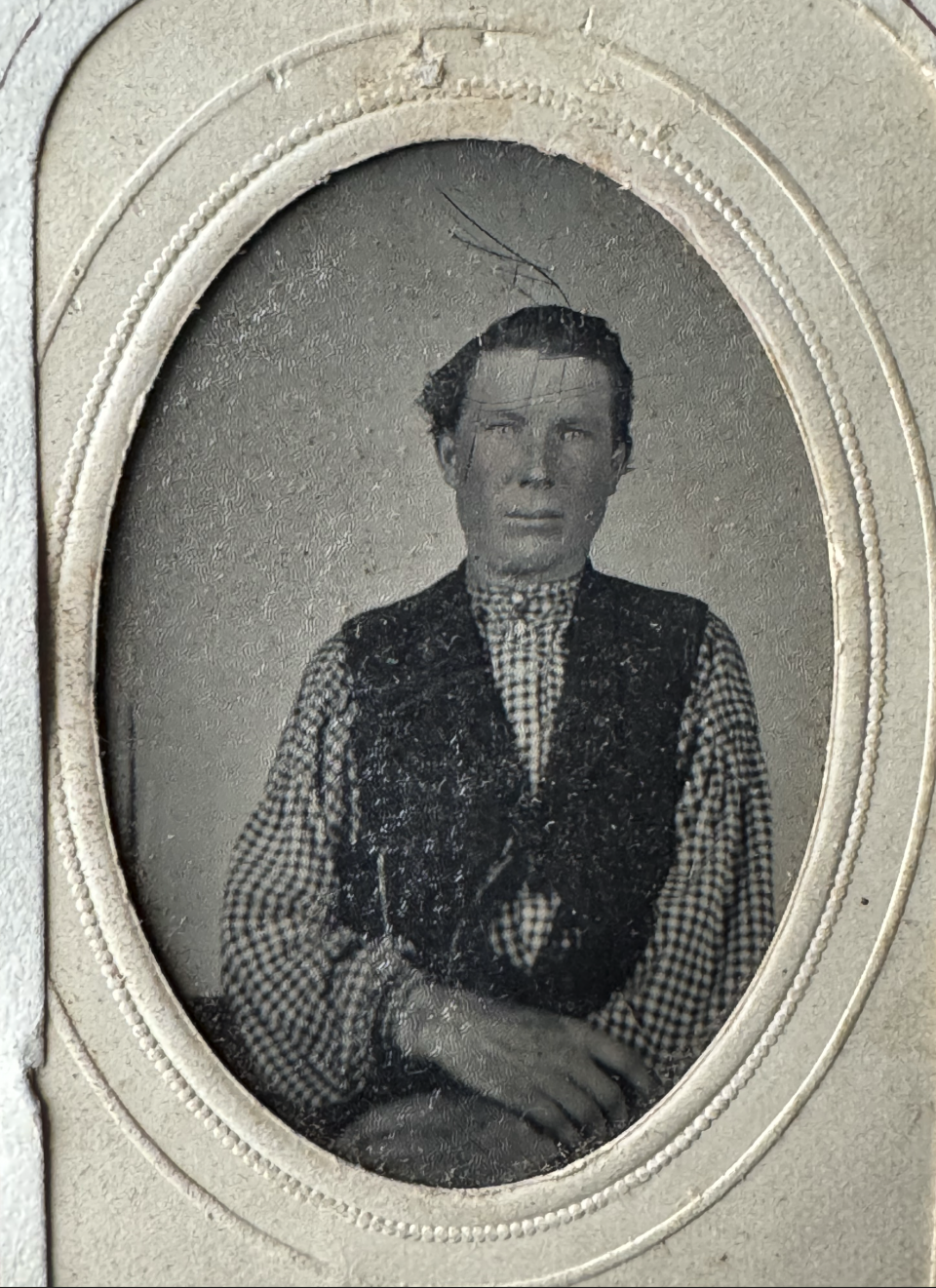 Tintype portrait of Dan Cox, whose name was written in pencil on the album mount. Ink markings over the surface of the photo almost look like a crude drawing of an Indian headband with one feather.