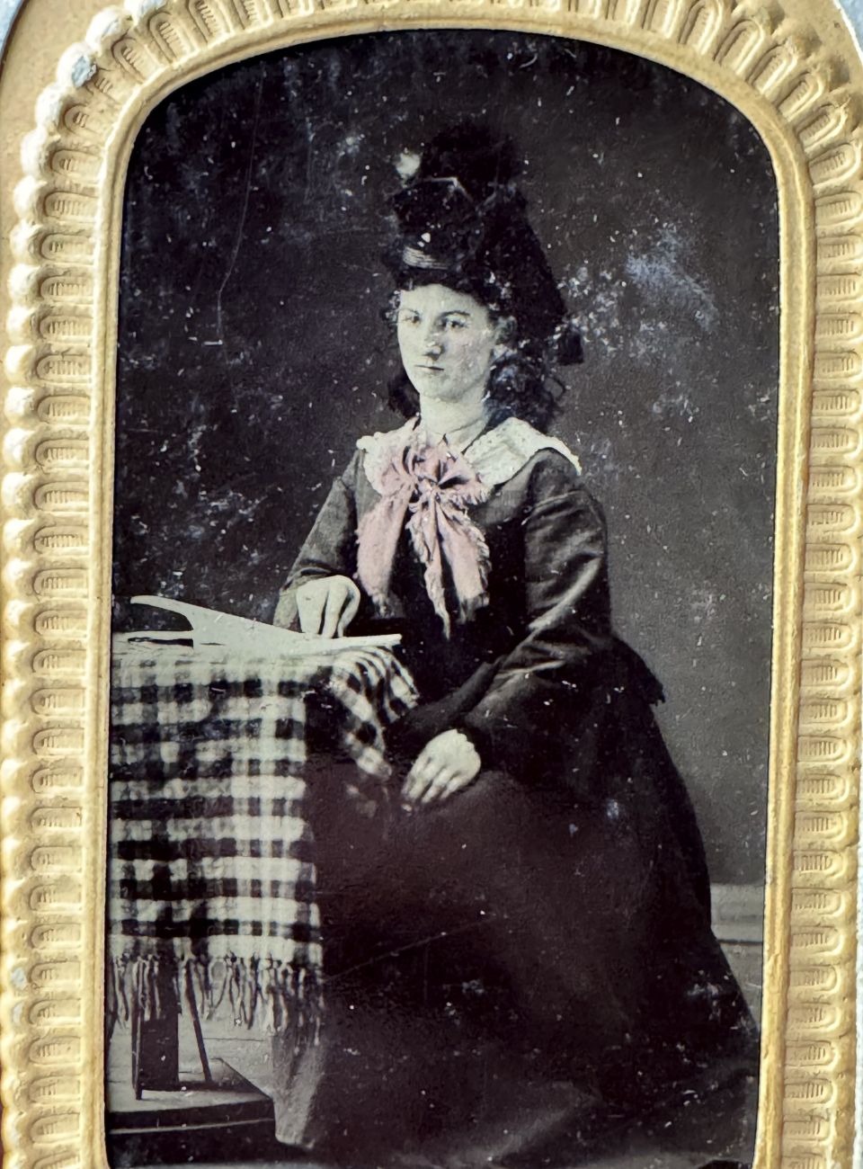 Close-up image of a tintype portrait of an unidentified young woman with a large hat and hand-colored pink scarf.